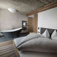 Schlafzimmer mit gemütlichem Bett und Badewanne