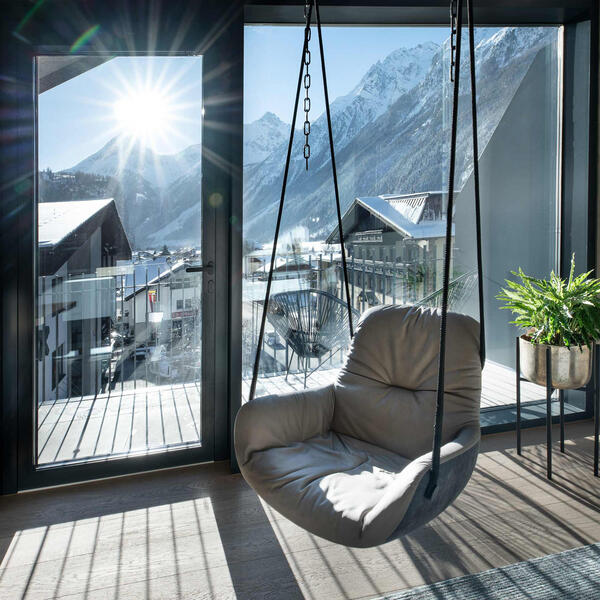 Wohnzimmer mit Hängesessel und großem Balkon mit Bergblick