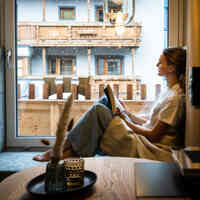 Ein Gast liest ein Buch beim Panoramafenster 